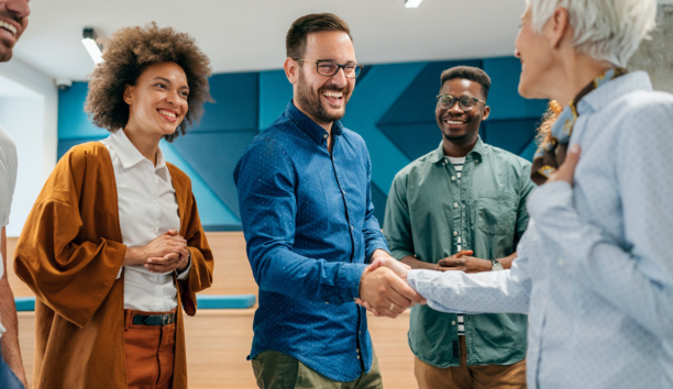 New hire shaking hands and meeting smiling coworkers.