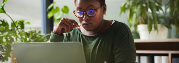 Female employee with glasses looking at laptop.
