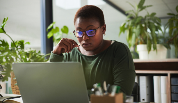 Female employee with glasses looking at laptop.