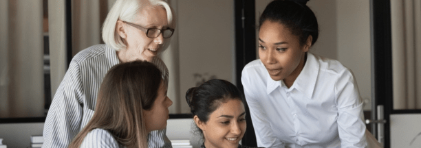 Multigenerational female employees working in a conference room together.