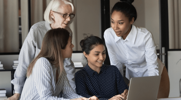 Multigenerational female employees working in a conference room together.