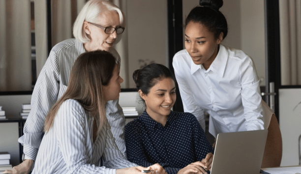 Multigenerational female employees working in a conference room together.