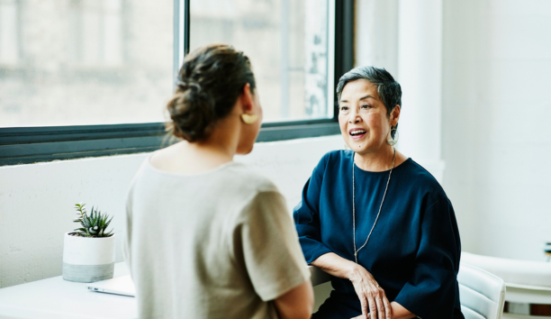 Benefits administrator meeting with an employee as they face each other.