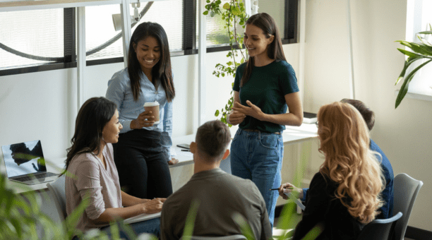 Young adult employees talking and laughing in a conference room.