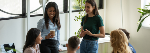 Young adult employees talking and laughing in a conference room.